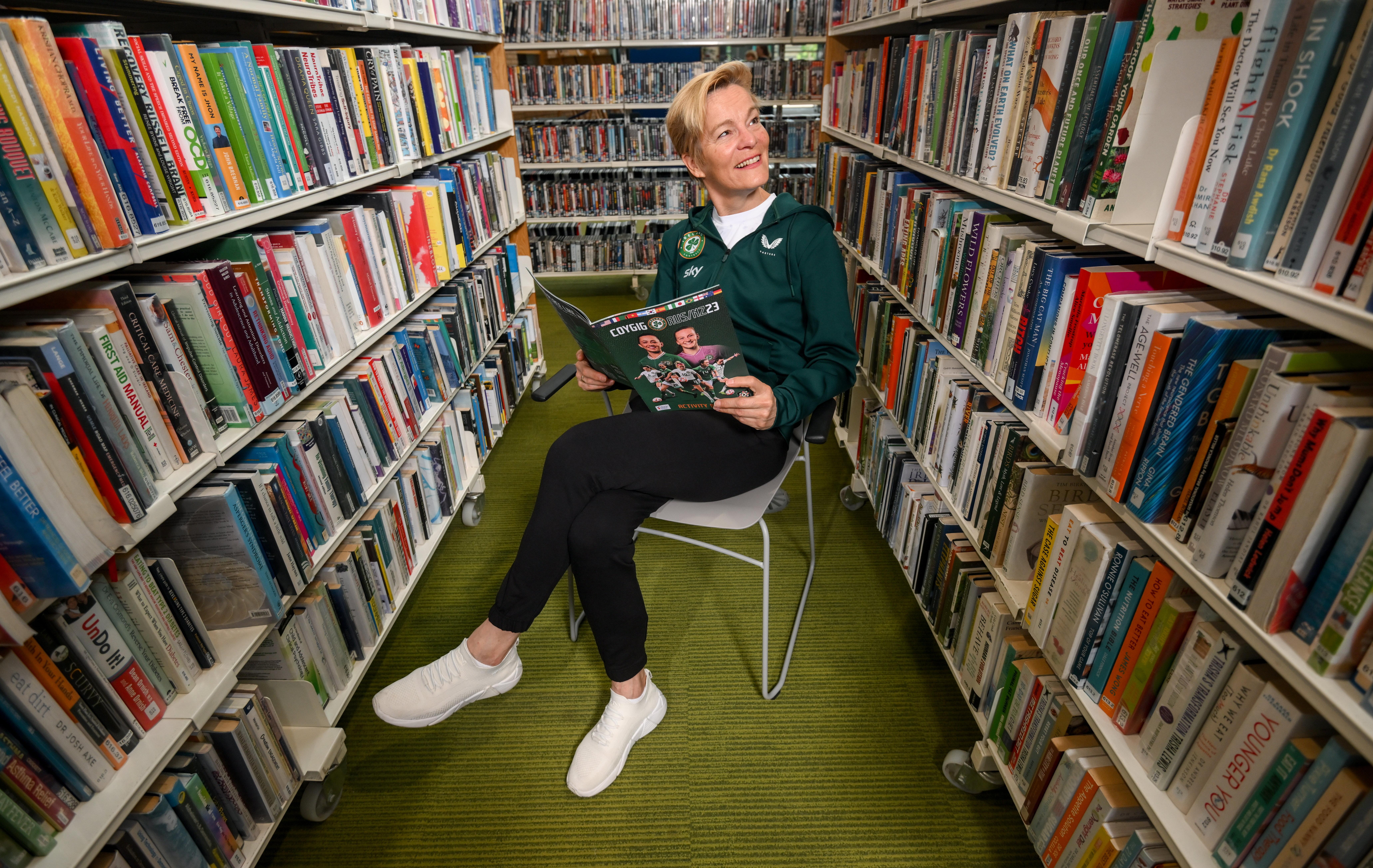 Woman sitting in library stacks reading a book